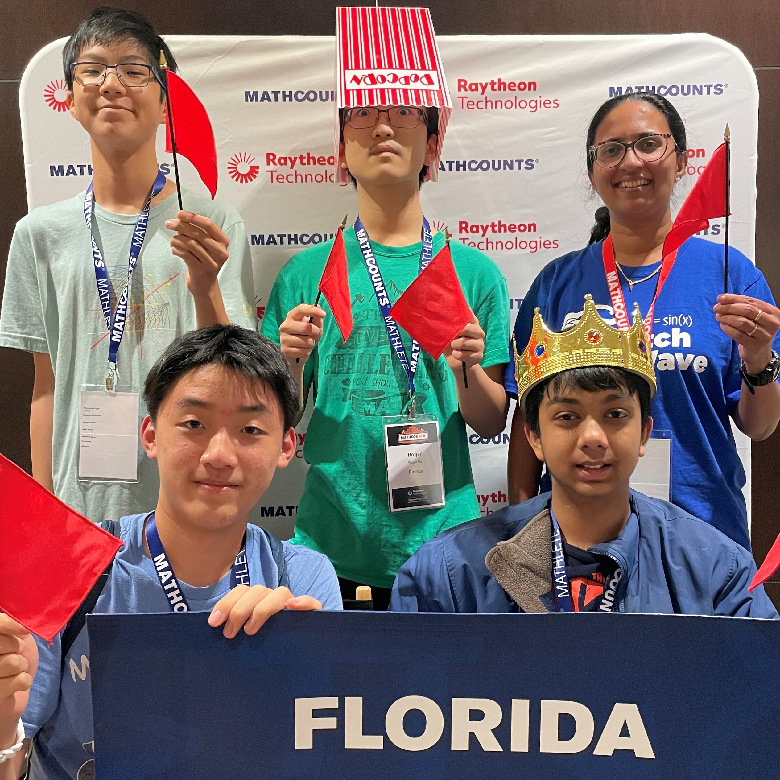 Team florida (4 boys and coach) smile with props in front of a photo booth with their team sign.